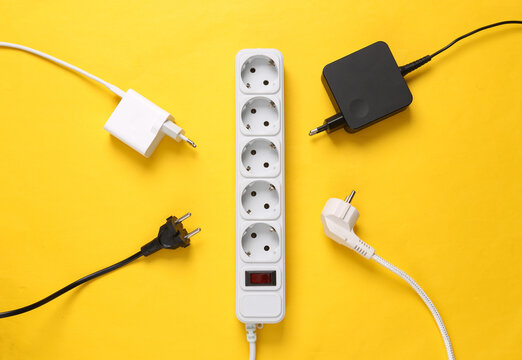 Electrical Extension cord with different plugs and adapters on yellow background. Top view.