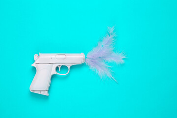 Minimal layout. White gun with feathers on a turquoise background.