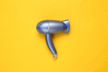 Hair dryer on yellow background. Minimal beauty layout. Top view. Flat lay