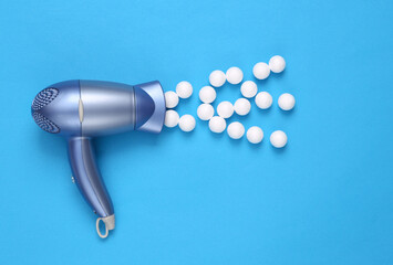 Fototapeta premium Hair dryer with balls on blue background. Minimal beauty layout. Top view. Flat lay