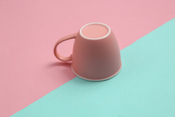 Inverted cup on a blue-pink pastel background. Minimal layout