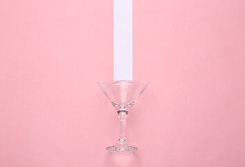 Cocktail empty glass on pink pastel background with white stripe. Minimalism. Top view
