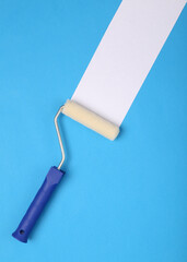 Paint roller with white stripe on a blue background. Home renovation concept