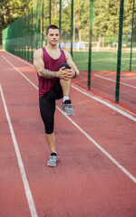 Obraz premium Athletic muscular man warming up before training at the stadium. Healthy lifestyle