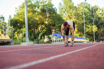 Athletic man with a naked torso practicing stretching exercise before running to the stadium. Healthy lifestyle