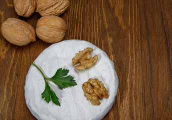 A circle of camembert cheese lies on a wooden board.
