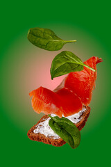 sandwich with lightly salted trout, cheese, spinach on a green background