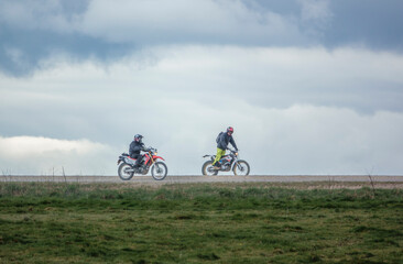 a pair of motorcyclists (bikers) riding off-road motorbikes along a stone track on Salisbury Plain, Wiltshire