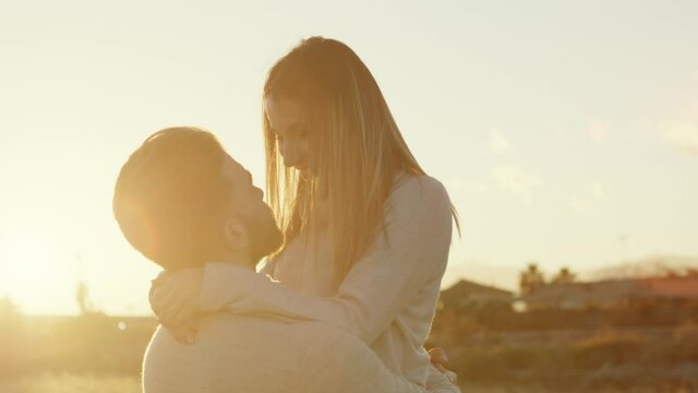 Coppia di ragazza e ragazzo si abbracciano al tramonto in un parco per San Valentino