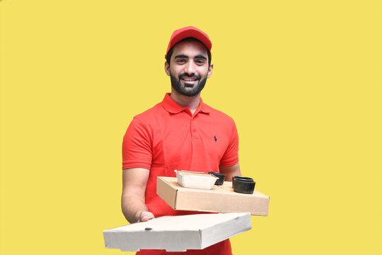 delivery man smiling in red t shirt and cap holding 2 pizza box indian pakistani model
