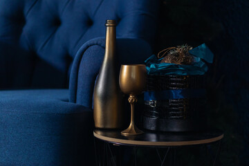 Still life in blue and gold. There is a bottle of champagne, a glass and a box with Christmas...