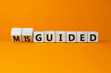 Guided or misguided symbol. Turned wooden cubes and changed the word misguided to guided. Beautiful orange table, orange background, copy space. Business and guided or misguided concept.