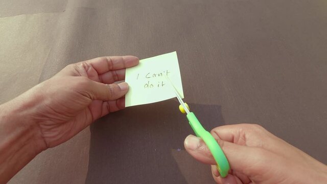 Hands cutting letter T from can&rsquo;t with scissors written text on sticky reminder paper. Determination Success Challenge believe Motivation aspirations to achieve results Aim goal Business concept.