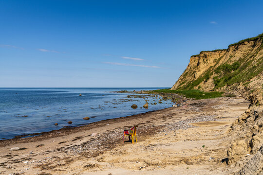 The Baltic Sea coast with an empty plastic chair on the beach and the cliffs of Boltenhagen, Mecklenburg-Western Pomerania, Germany