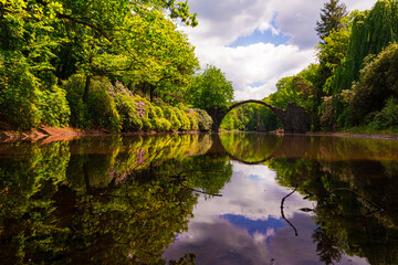 Spiegelung der Rakotzbrücke rund Kreis in Kromlau Park mit Bäumen und Teich Wasser