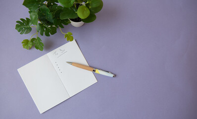 Liste des choses à faire en écriture manuscrite au stylo à bille dans un petit cahier à pages blanches avec des plantes vertes à feuilles sur fond mauve - obrazy, fototapety, plakaty