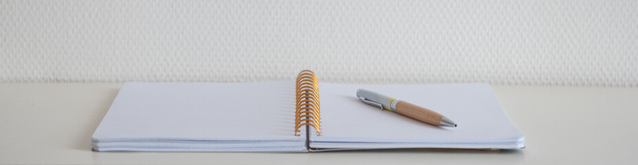 Cahier à spirale ouvert sur une page blanche avec un stylo sur un bureau blanc pour trouver l'inspiration d'écrire et la motivation de travailler