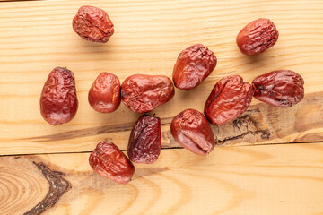 Several sweet dried ziziphus berries on a wooden table, close-up, top view.