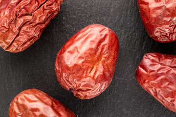 Five sweet dried ziziphus berries on a slate stone, close-up, top view.