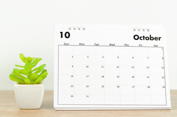 October 2022 desk calendar with plant pot on wooden table.