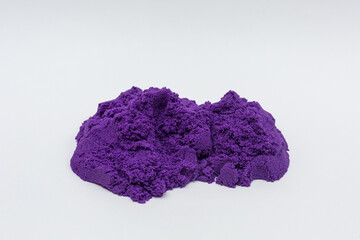 Scattered kinetic sand of purple color on a white background.