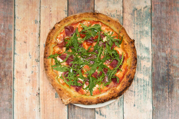 Top view image of Iberian ham pizza with arugula and mozzarella cheese with cherries tomatoes