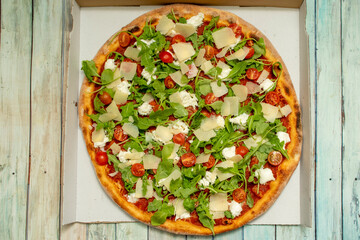 Top view image of Iberico ham pizza with arugula and mozzarella cheese and parmesan cheese flakes with cherries tomatoes