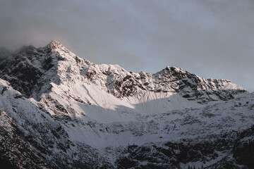 Schnee auf Bergen in den Alpen mit Sonnenstrahlen und Nebel im Winter