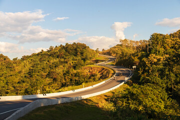 Fototapeta premium Curve road No. 3, or sky road on Root 1081 over top of mountains with green jungle in Santisuk - Bo Kluea District. Beautiful landscape scenic of road number three at Nan, Thailand.