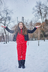 a young happy woman is having fun in a winter park, throwing snow, it is cold in her hands, the emissions are off scale.