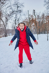 a young happy man is having fun in a winter park, throwing snow, it is cold in his hands, the emissions are off scale.