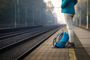 Solo traveler waiting for train at empty railroad station. Woman with backpack standing at railway platform - Powered by Adobe