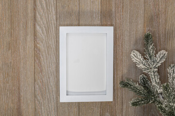 White frame mockup on wooden board and evergreen for winter or Christmas