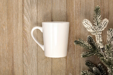 White mug mockup on wooden board and evergreen for winter or Christmas