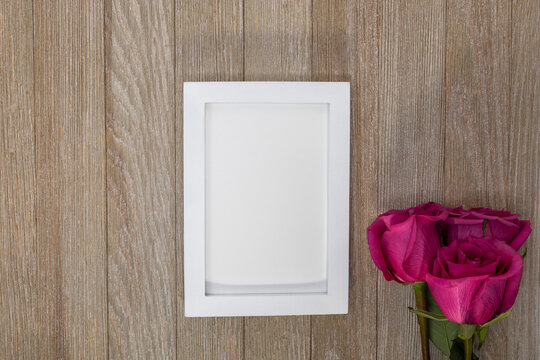 White frame mockup on rustic wooden board with pink roses for Valentine's Day, Mother's Day, Anniversary