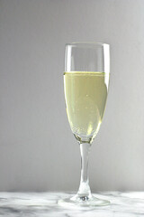One glass of champagne is on a gray marble table. New year drink