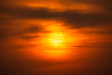 Orange sky and sun shining behind clouds nature background