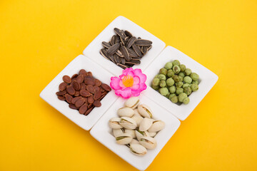 Tet Holiday, Lunar new year, chinese new year concept . Dried sunflower, lotus, watermelon and pumkin seeds top view isolated on yellow. Tet snacks