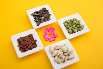 Tet Holiday, Lunar new year, chinese new year concept . Dried sunflower, lotus, watermelon and pumkin seeds top view isolated on yellow. Tet snacks