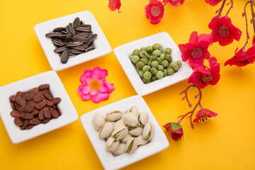 Tet Holiday, Lunar new year, chinese new year concept . Dried sunflower, lotus, watermelon and pumkin seeds top view isolated on yellow. Tet snacks