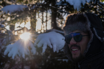 Latin American man with sunglasses walking in the woods in winter 