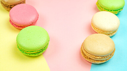 Multicolored macaroon cakes on colored bedding background with copy space
