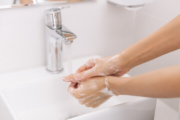 Washing hands under the flowing water tap. Washing hands rubbing with soap for corona virus prevention, hygiene to stop spreading corona virus in or public wash room. Hygiene concept hand detail