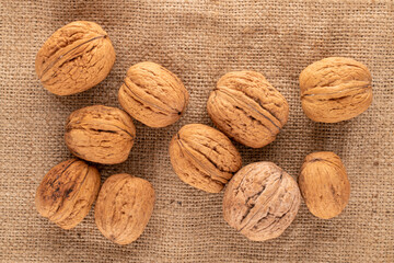 Several organic walnuts on burlap, close-up, top view.