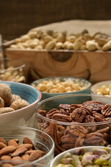 Different nuts and bowls closeup on a wooden table and brown background. Peanut, nut, cashew, almond, hazelnut, pistachio