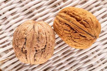 Two organic walnuts on a vine mat, close-up, top view.