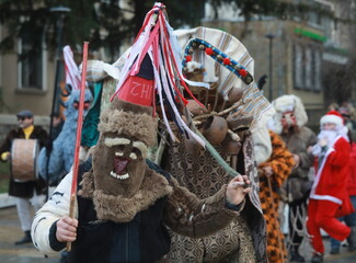 Fototapeta na wymiar Godech, Bulgaria - January 1, 2022: Mummers in traditional costumes toured the streets of Godech on the first day of 2022. People with a mask called Kukeri dance and perform to scare the evil spirits