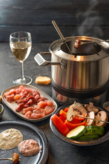 Fondue from vegetables and meat cooked at the table in a pot with boiling broth or hot oil, served...