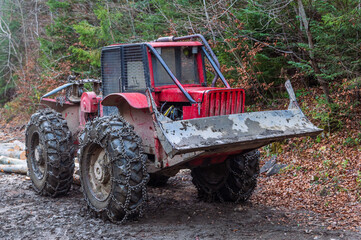 The red skidder in the forest. The timber skidding machine. Large rubber wheels with chains facilitate movement in difficult terrain
