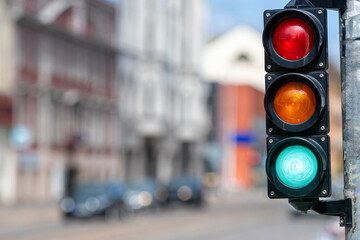 closeup of small traffic semaphore with green light against the backdrop of the city traffic